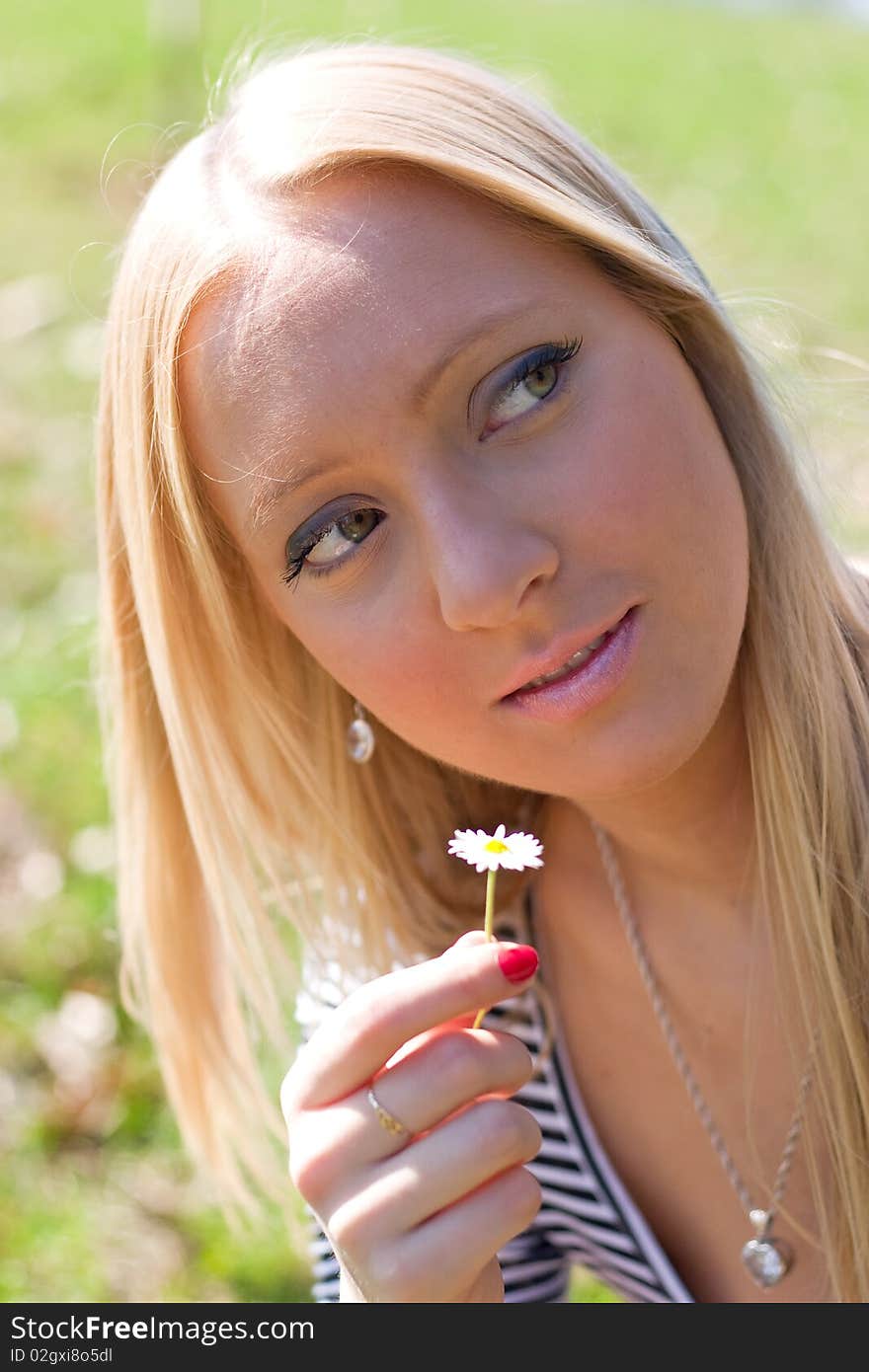 Blond girl in nature holding Daisy flower