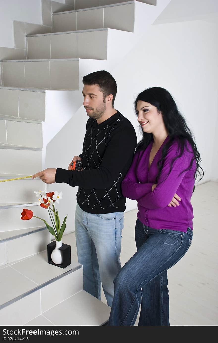 Young couple moving in new house,they measuring the stairs and planning together in an empty room with white wooden floor unfinished,see more in <a href=http://www.dreamstime.com/people-on-couch-or-wooden-floor-rcollection11965-resi828293>People on couch or wooden floor</a>. Young couple moving in new house,they measuring the stairs and planning together in an empty room with white wooden floor unfinished,see more in <a href=http://www.dreamstime.com/people-on-couch-or-wooden-floor-rcollection11965-resi828293>People on couch or wooden floor</a>