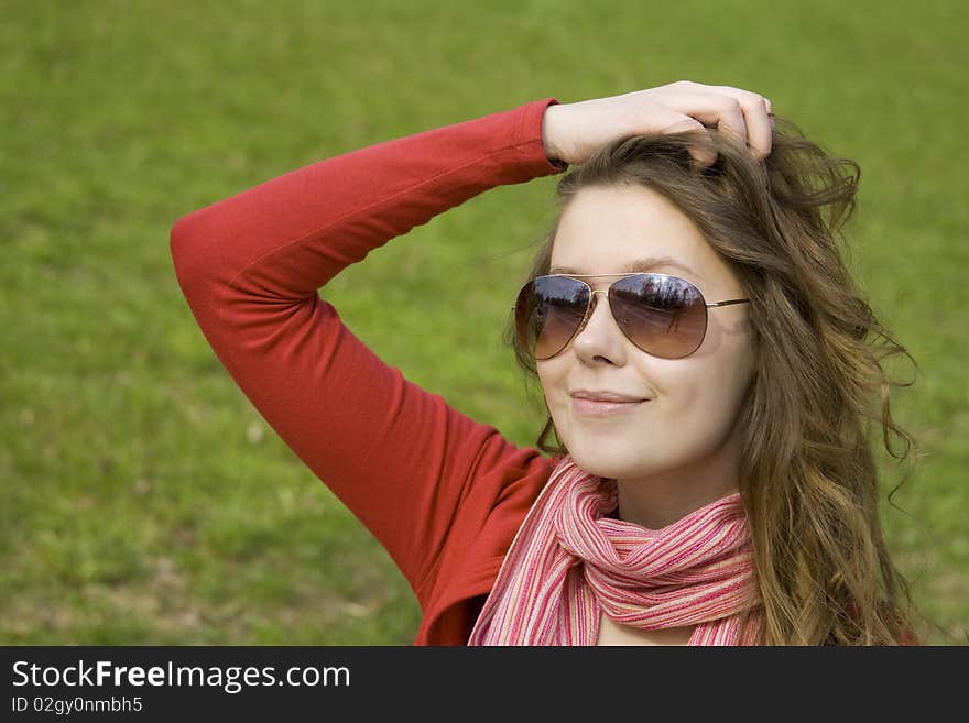 A beautiful young woman in sunglasses relaxing in the park on a bench. Straightens his hair. A beautiful young woman in sunglasses relaxing in the park on a bench. Straightens his hair.