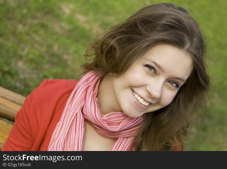 A beautiful young woman relaxing in the park on a bench. Laughs. A beautiful young woman relaxing in the park on a bench. Laughs