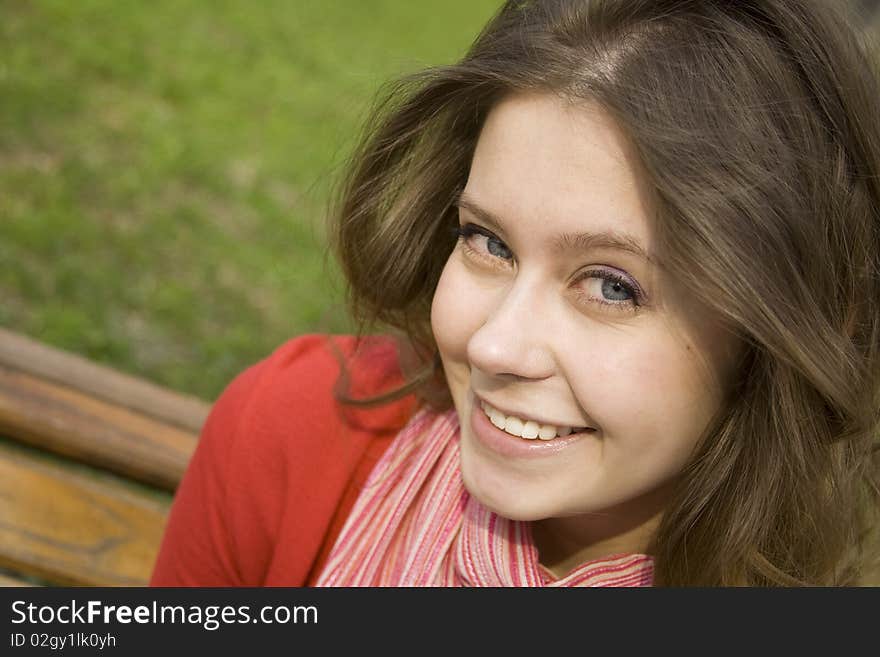 A beautiful young woman relaxing in the park on a bench. Laughs. A beautiful young woman relaxing in the park on a bench. Laughs