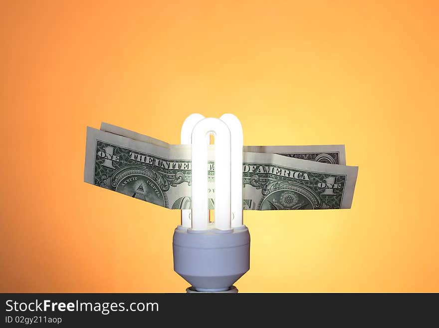 Energy saving compact fluorescent lightbulb and one dollar note on ginger background. Energy saving compact fluorescent lightbulb and one dollar note on ginger background