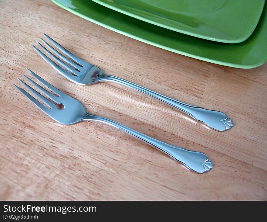 Two forks and green plate over wood table. Two forks and green plate over wood table