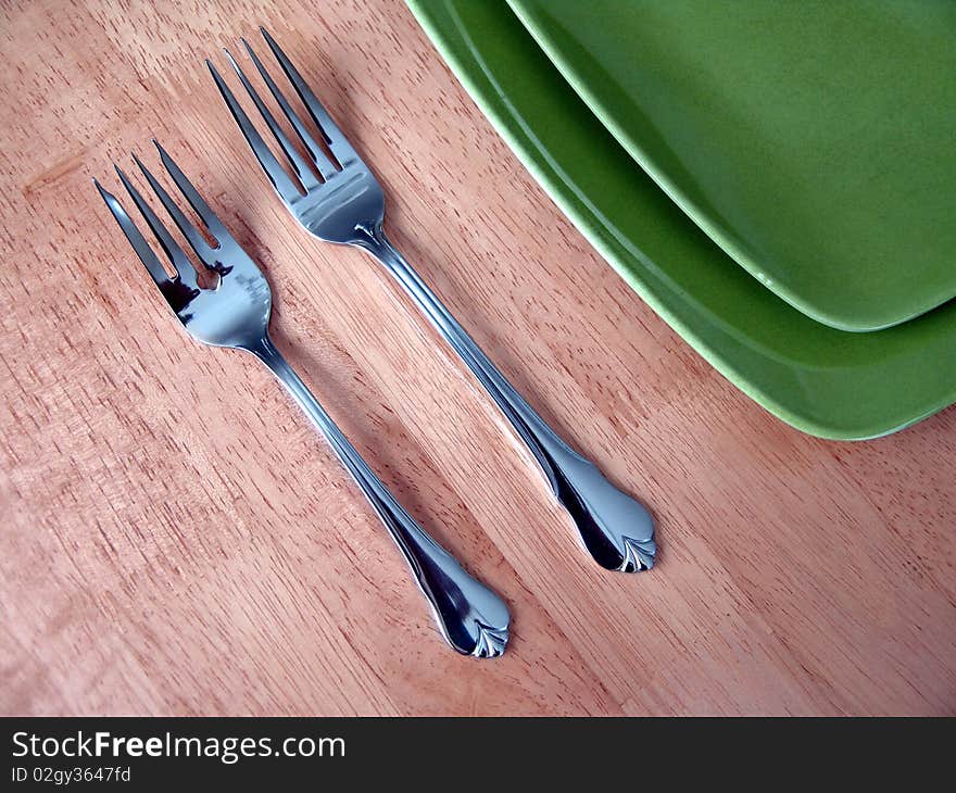 Two forks and green plate over wood table. Two forks and green plate over wood table