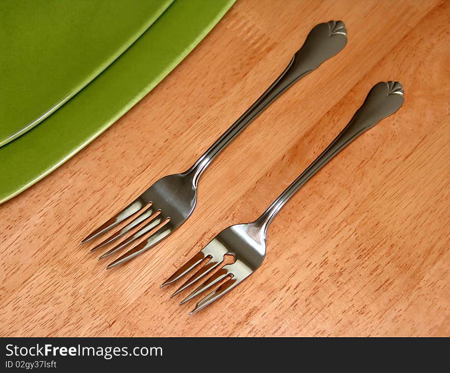 Two forks and green plate over wood table. Two forks and green plate over wood table