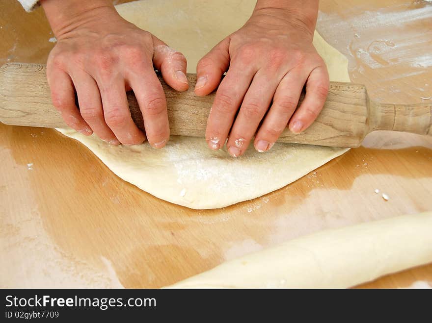 Hands on rolling pin over dough