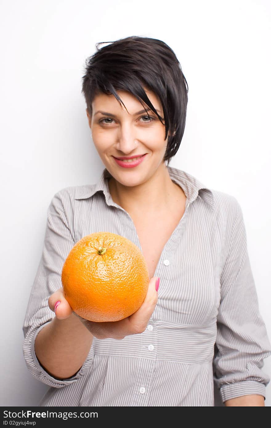 Girl offering a fresh orange (focus on orange). Girl offering a fresh orange (focus on orange)