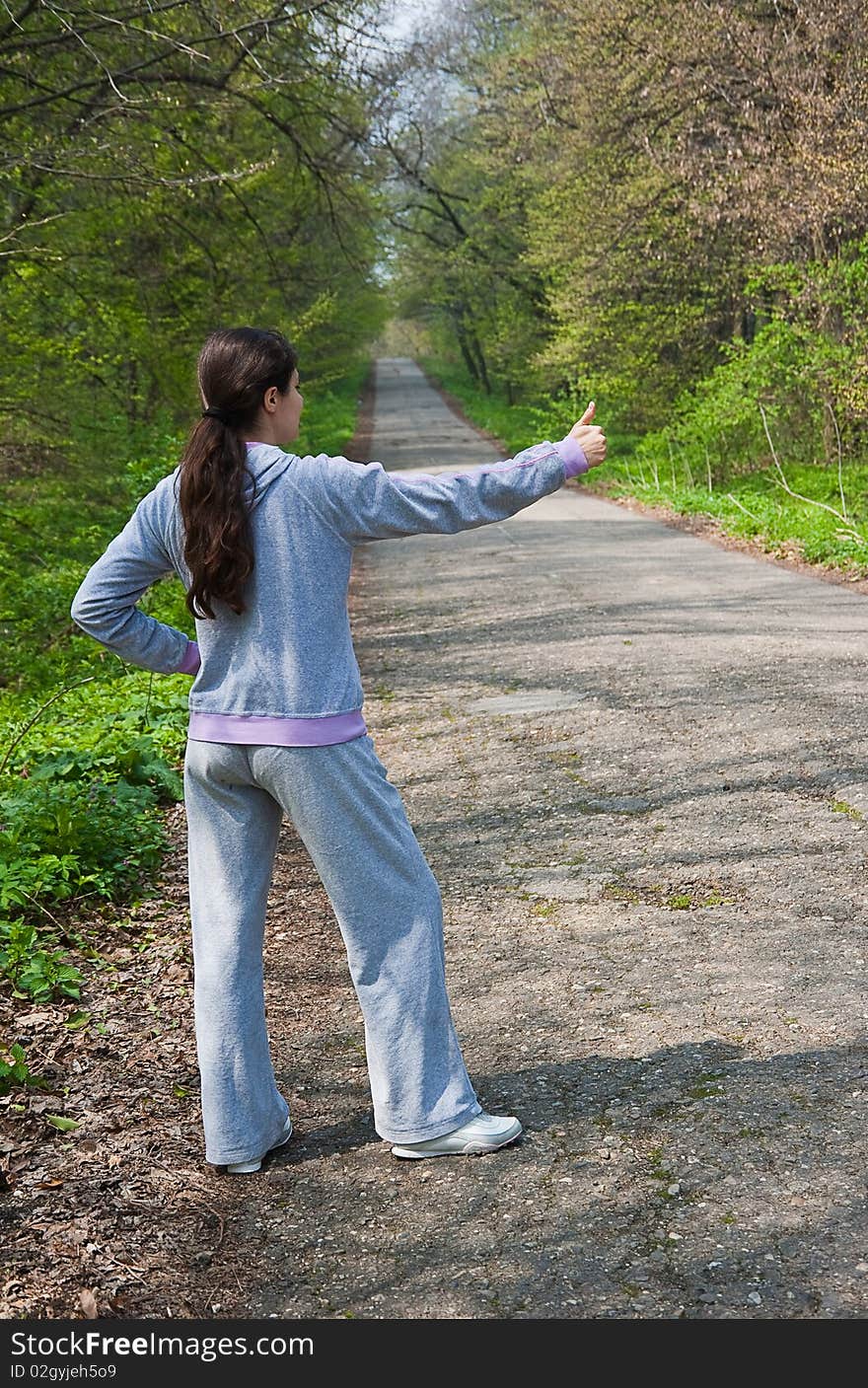 Girl hitch hiking near a forest road