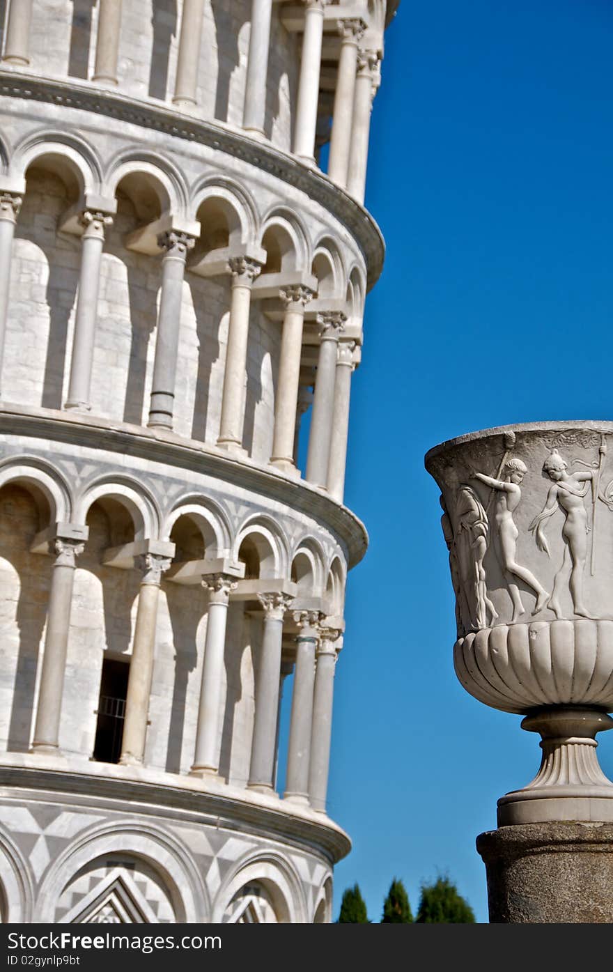 An urn, with a section of the leaning tower of Pisa in the background. An urn, with a section of the leaning tower of Pisa in the background.