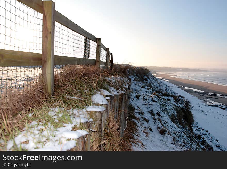 Cliff edge fence over a beach on a cold winters day. Cliff edge fence over a beach on a cold winters day