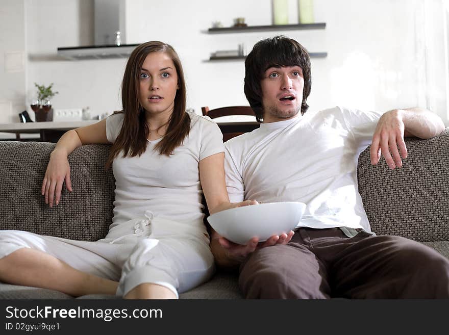 Boy with plate and girl with long hair on sofa. Boy with plate and girl with long hair on sofa