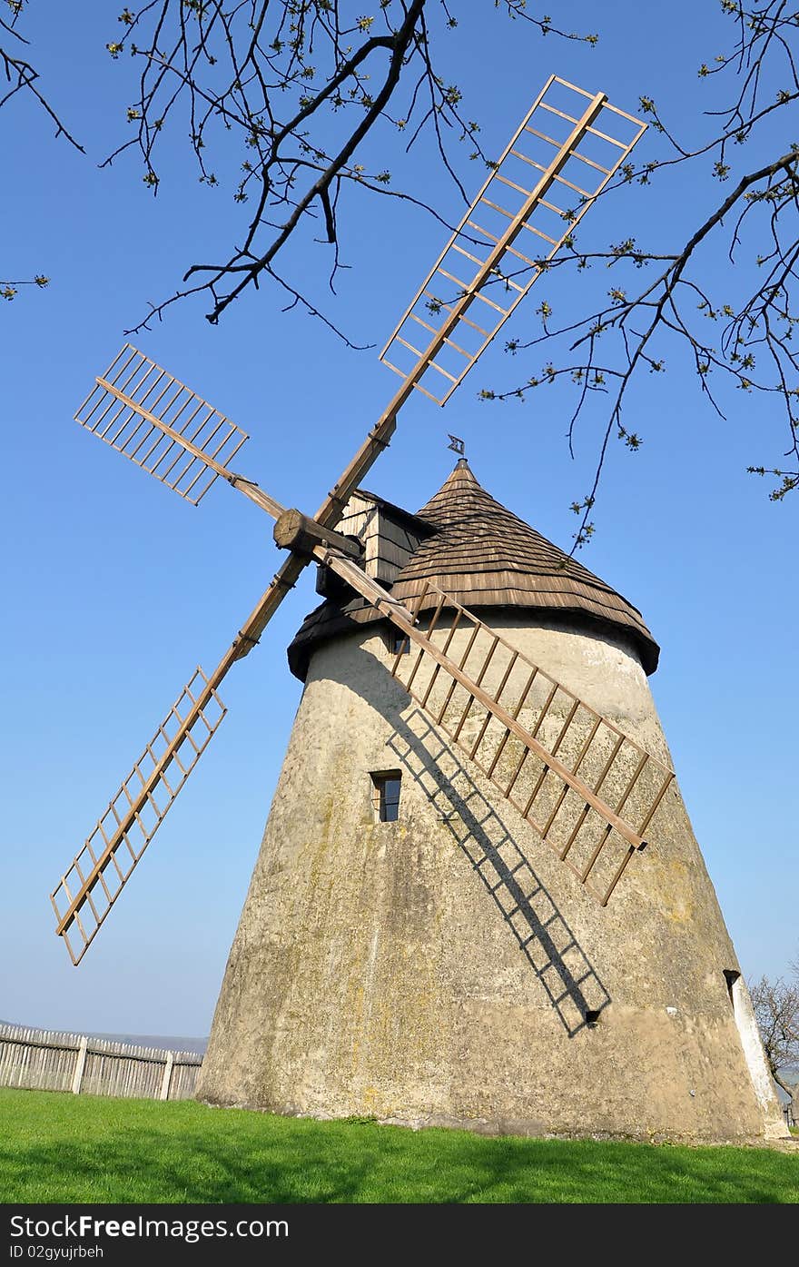 A windmill is a machine which converts the energy of wind to rotational motion by means of adjustable vanes called sails. The main use is for a grinding mill powered by the wind, reducing a solid or coarse substance into pulp or minute grains. A windmill is a machine which converts the energy of wind to rotational motion by means of adjustable vanes called sails. The main use is for a grinding mill powered by the wind, reducing a solid or coarse substance into pulp or minute grains.