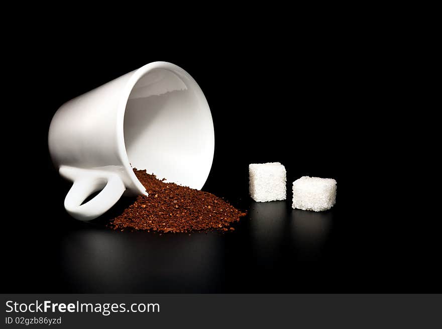 White cup, coffee powder, sugar cubes on a black background. White cup, coffee powder, sugar cubes on a black background