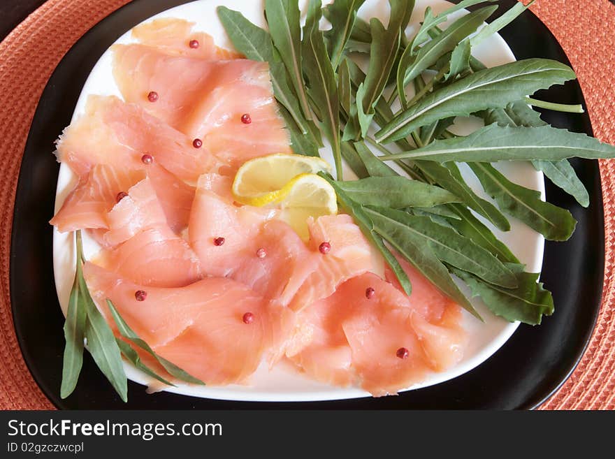 A dish of smoked salmon with red pepper and rocket. A dish of smoked salmon with red pepper and rocket