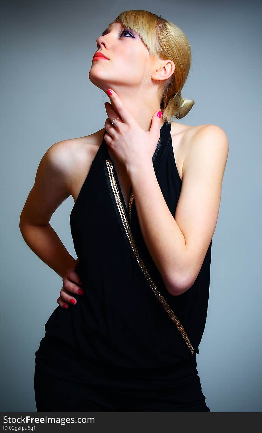 Young woman posing on grey background in black dress. Young woman posing on grey background in black dress