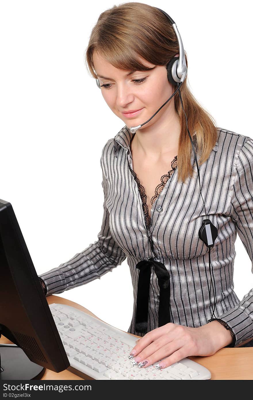 Beautiful young woman in headphones in front of her desktop computer on a white background. Beautiful young woman in headphones in front of her desktop computer on a white background