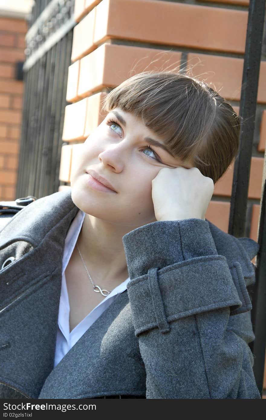 Girl thinking near red brick fence at the sunny day. Girl thinking near red brick fence at the sunny day