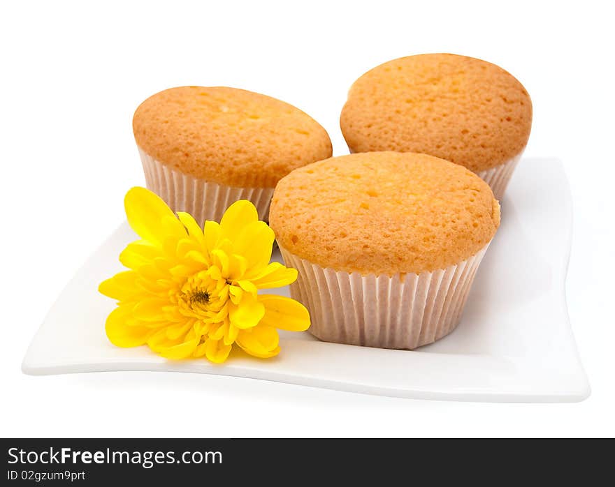 Gentle vanilla cakes on a white plate and a yellow camomile