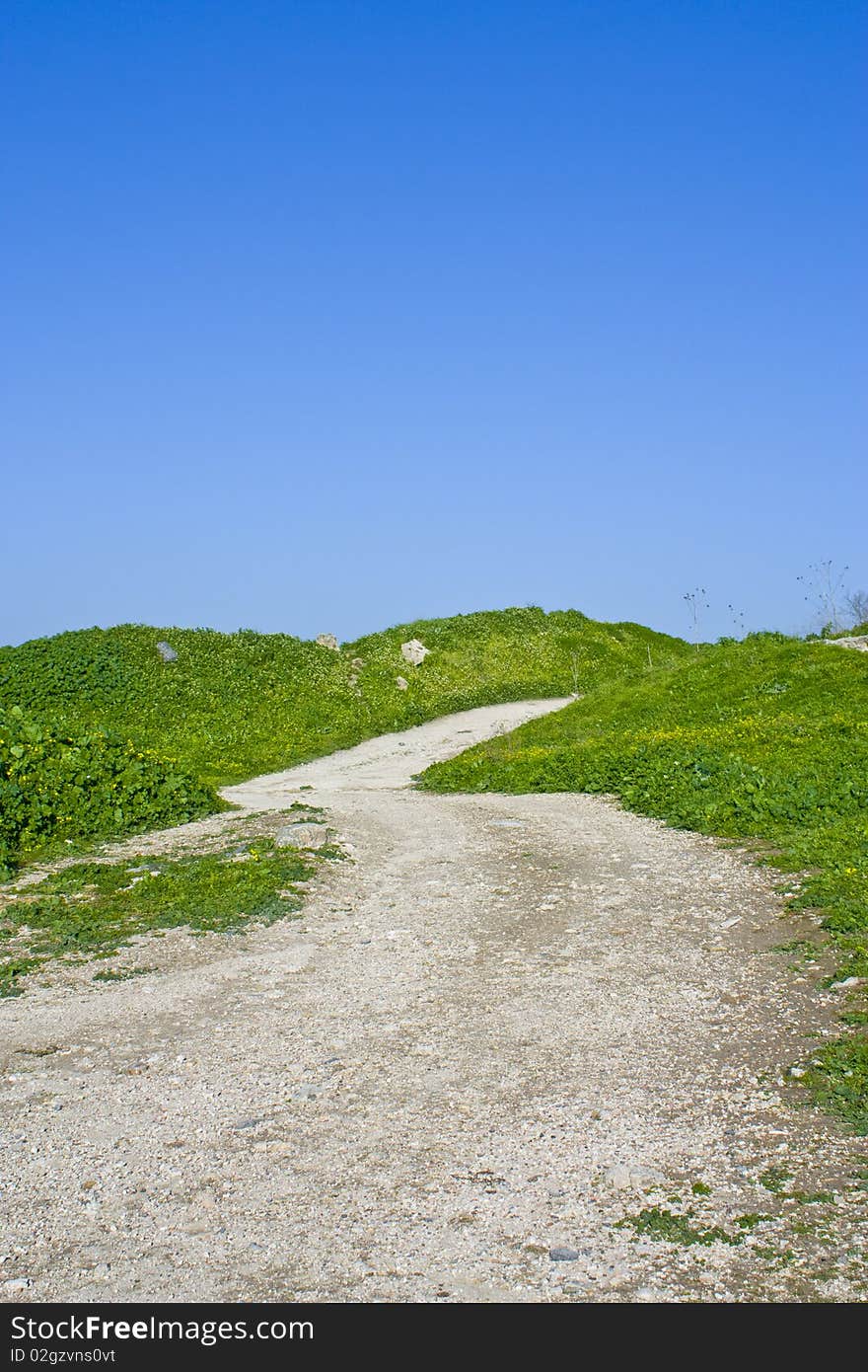 Photo of a dirt path through a green meadow over a blue clear sky, photo taken in Um-Qais - Jordan. Photo of a dirt path through a green meadow over a blue clear sky, photo taken in Um-Qais - Jordan