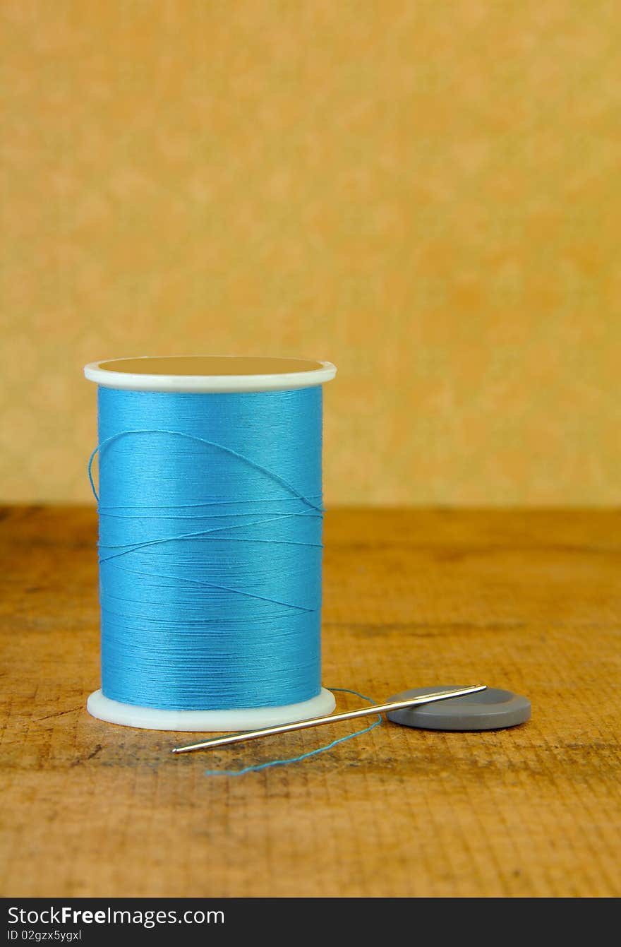 Spool of Blue Thread with a Needle and Button