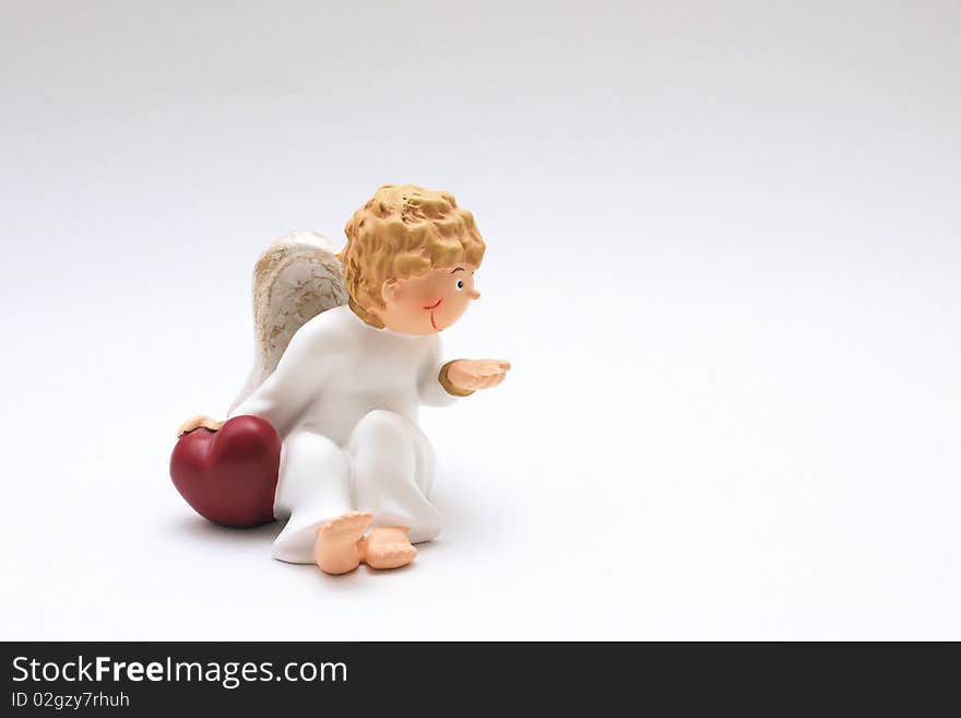 Figure of a curly-headed, childlike angel holding one hand on a red heart. Figure of a curly-headed, childlike angel holding one hand on a red heart