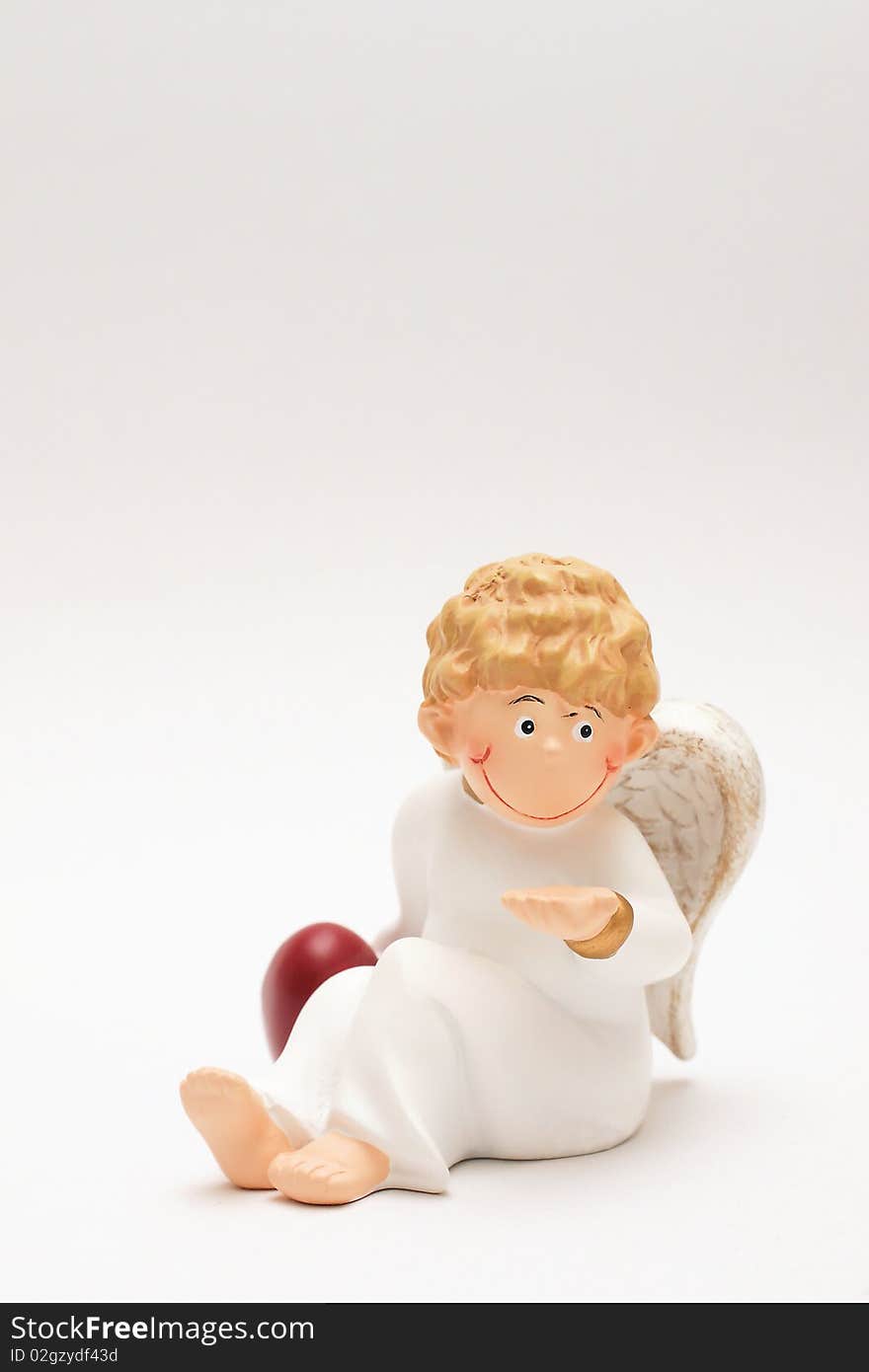 Figure of a curly-headed, childlike angel holding one hand on a red heart. Figure of a curly-headed, childlike angel holding one hand on a red heart