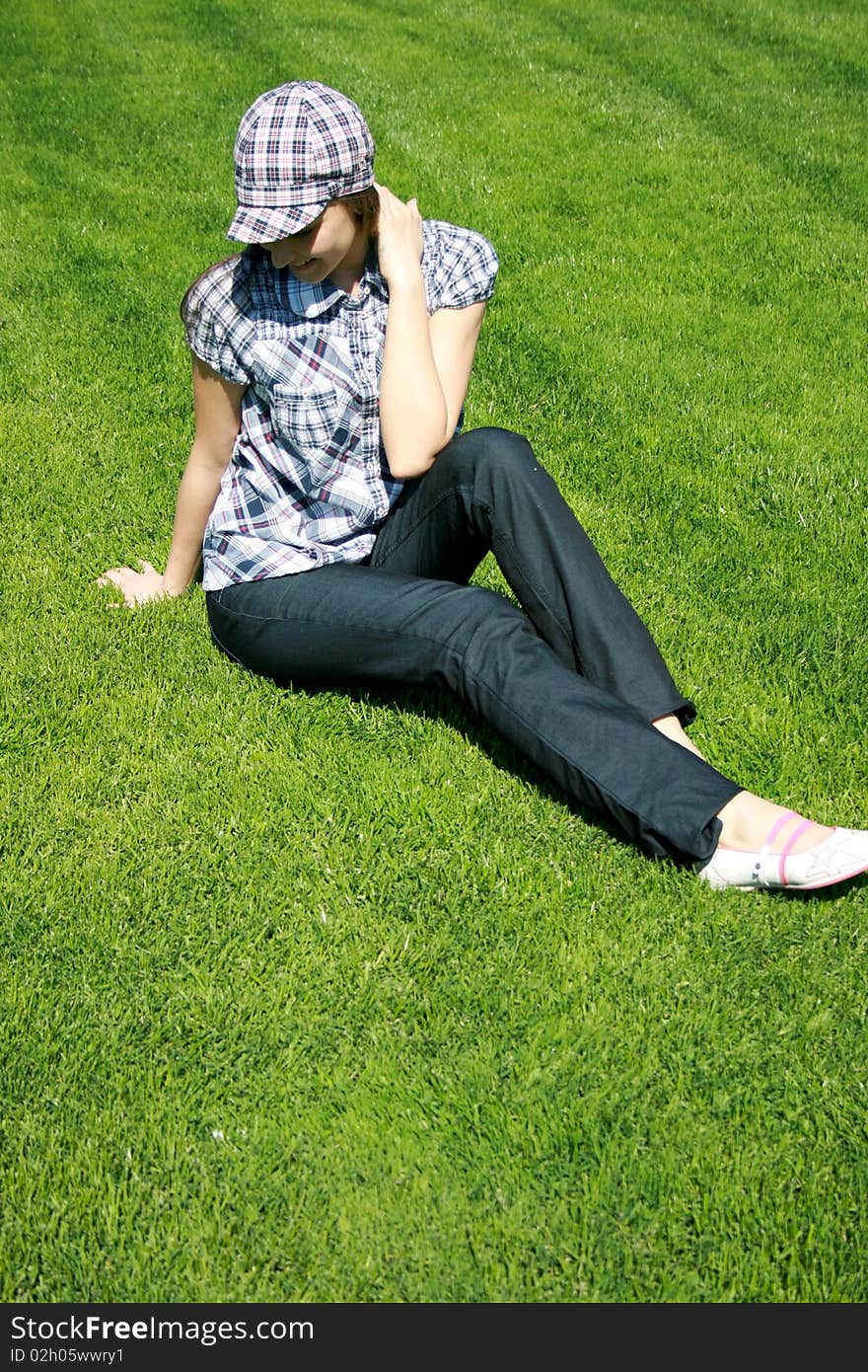 Young caucasian girl sitting on the green grass. Young caucasian girl sitting on the green grass