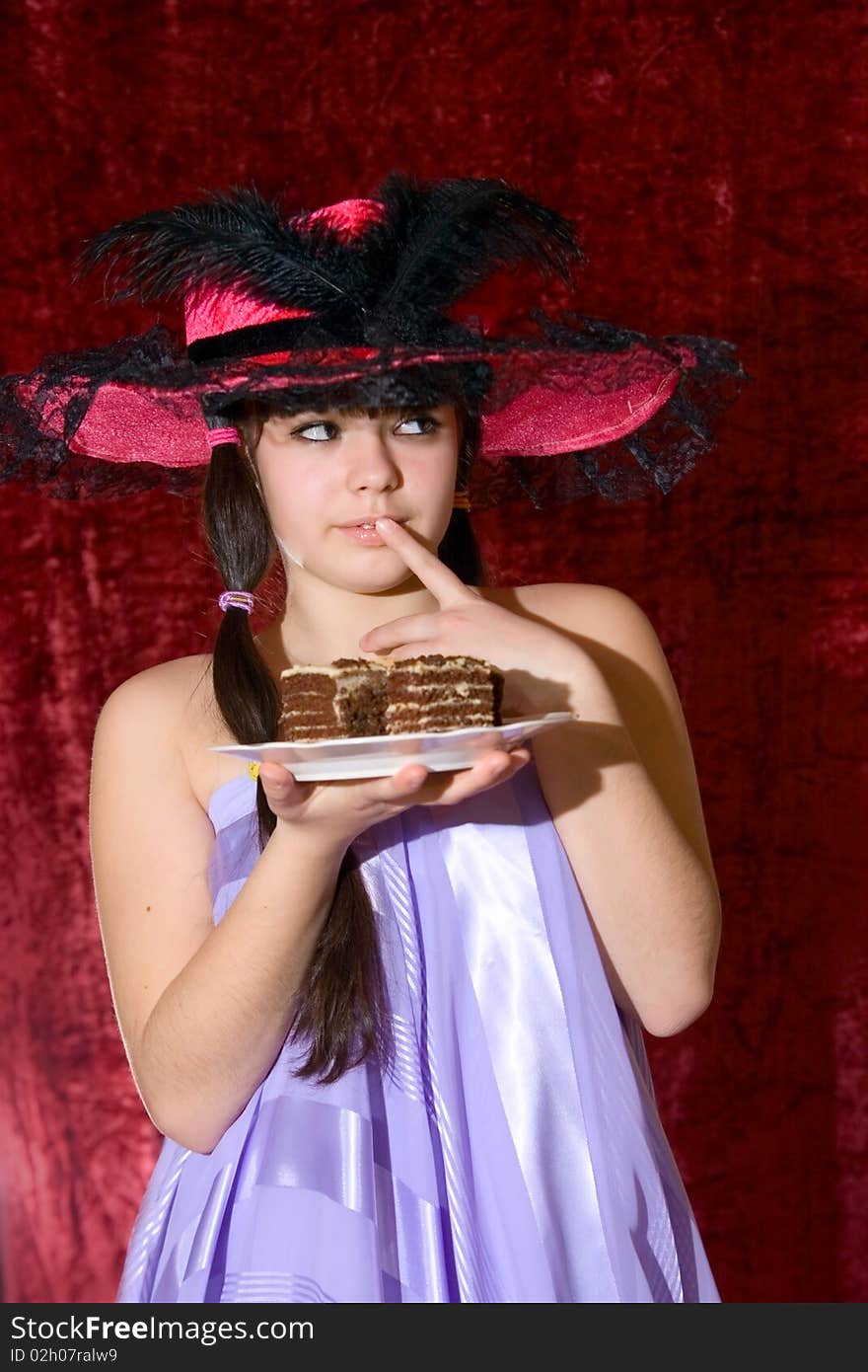 Lovely teen girl in dress and hat with cake