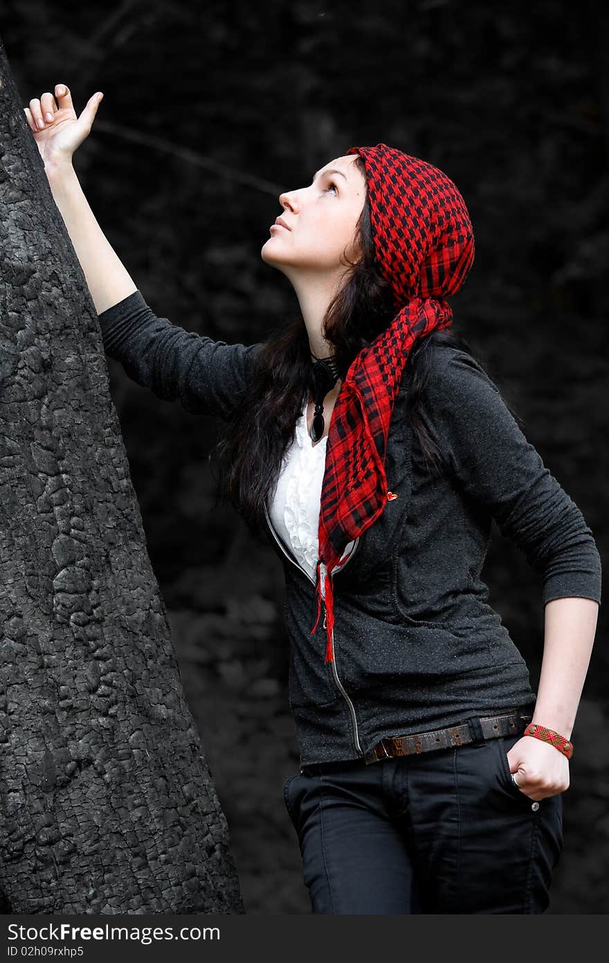 Girl in a red kerchief hugs charred wood. Girl in a red kerchief hugs charred wood