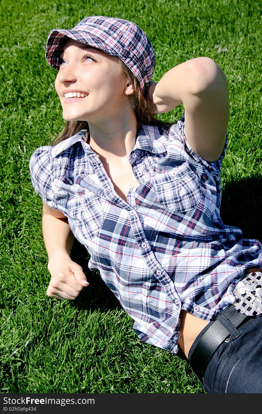 Young caucasian girl sitting on the green grass, spring rest