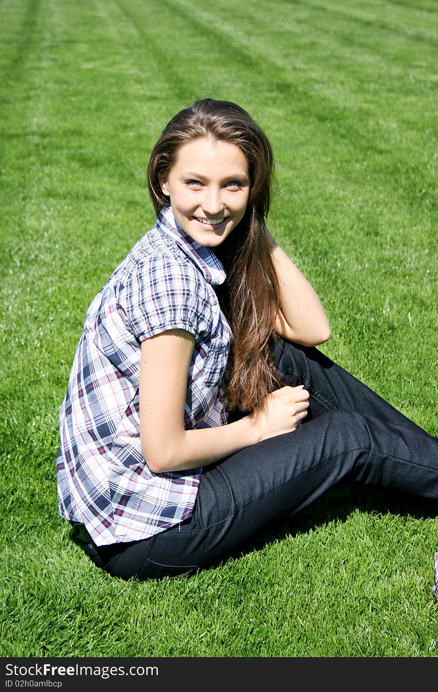 Young caucasian girl sitting on the green grass. Young caucasian girl sitting on the green grass