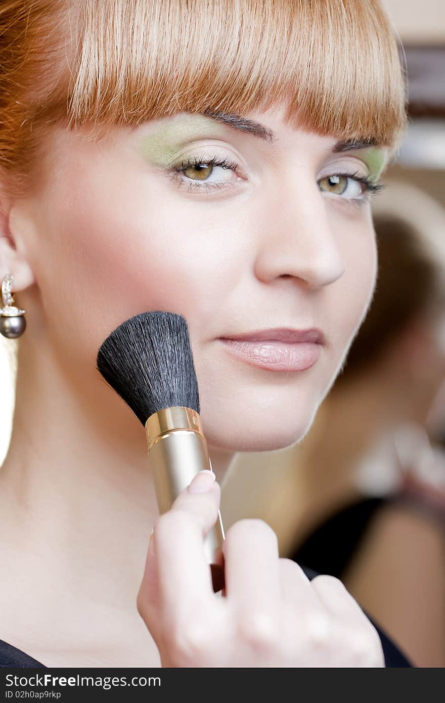 Beautiful young woman with a make-up brush