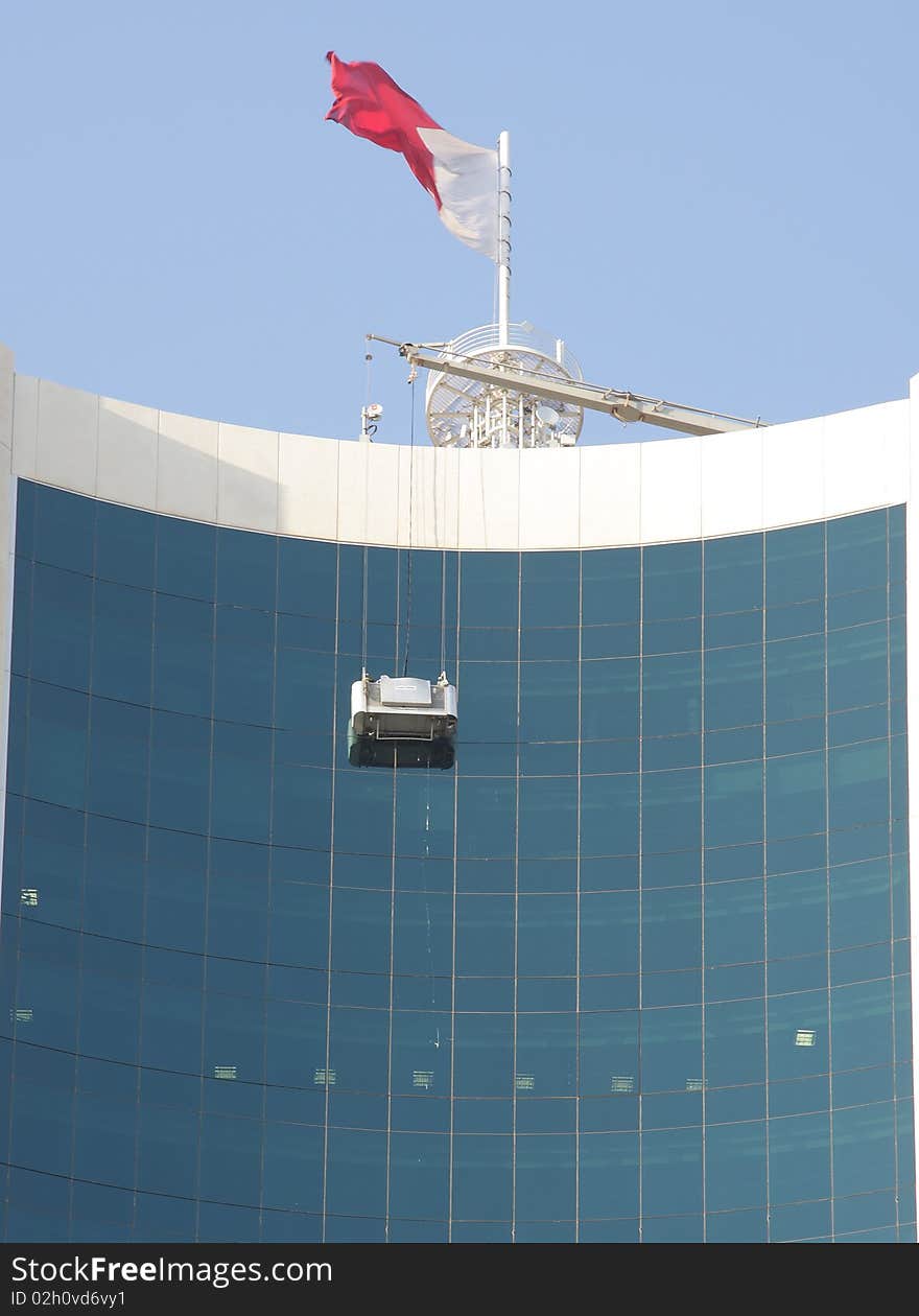 Cleaning of glasses in highrise building with the help of bucket hanged from the top. Cleaning of glasses in highrise building with the help of bucket hanged from the top