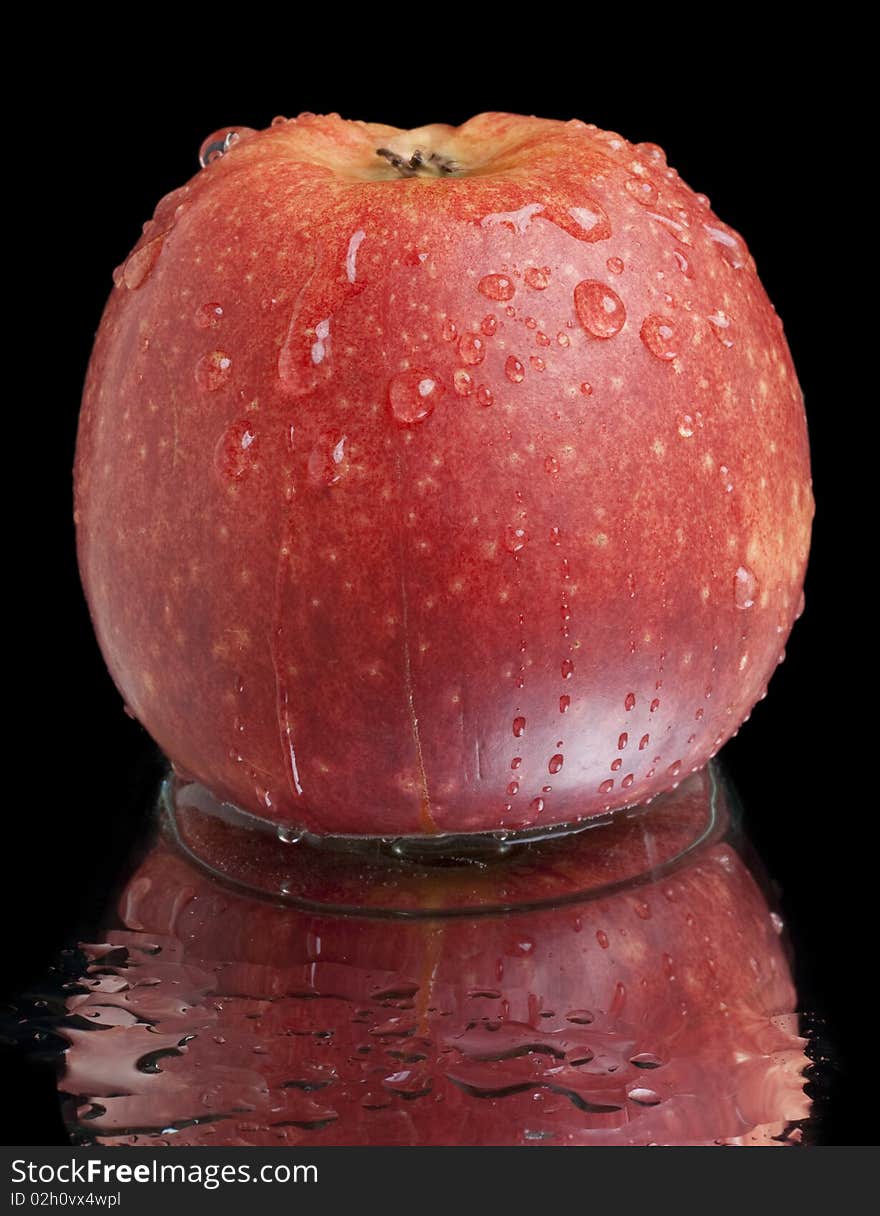 Wet red apple with reflection on black