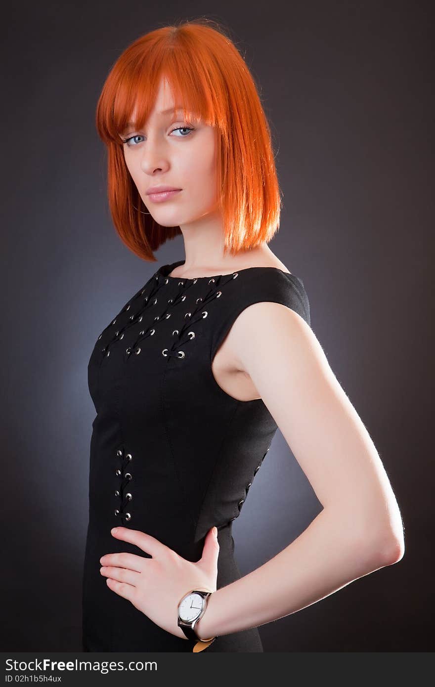 Beautiful red girl in an evening dress against a dark background