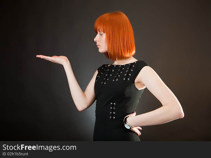 Beautiful red girl in an evening dress against a dark background. Beautiful red girl in an evening dress against a dark background