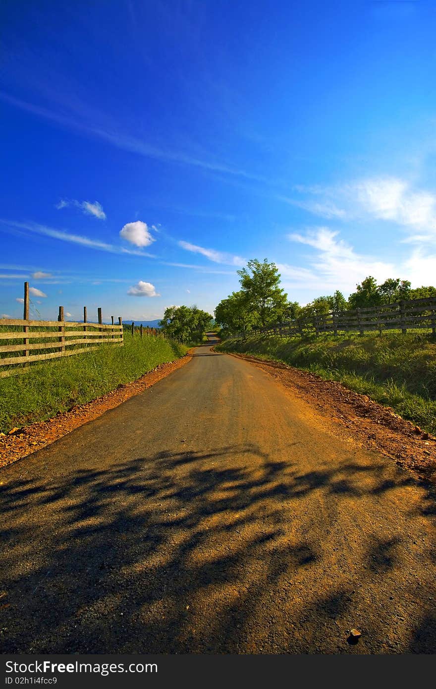 Simple village road with tree shadows.