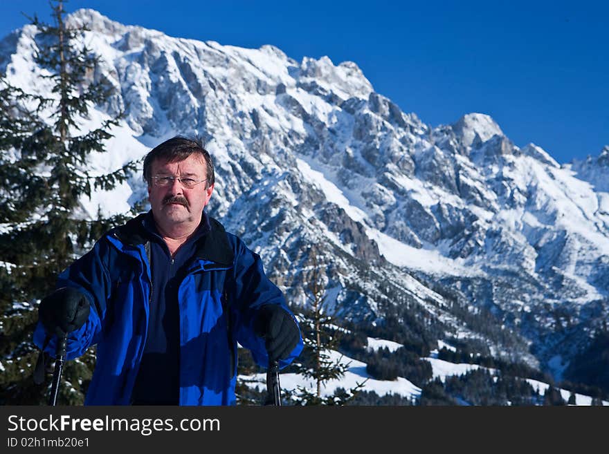 An active  senior man with snowshoes in a winter setting in the alps. An active  senior man with snowshoes in a winter setting in the alps.