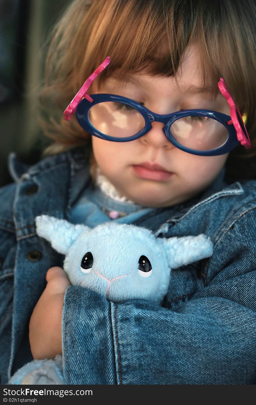 Focus is on the lamb's eyes. The girl is loving and/or coveting her special toy. Focus is on the lamb's eyes. The girl is loving and/or coveting her special toy.