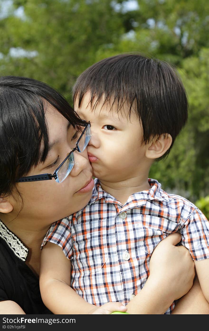 An Asian boy giving his mother a kiss. An Asian boy giving his mother a kiss