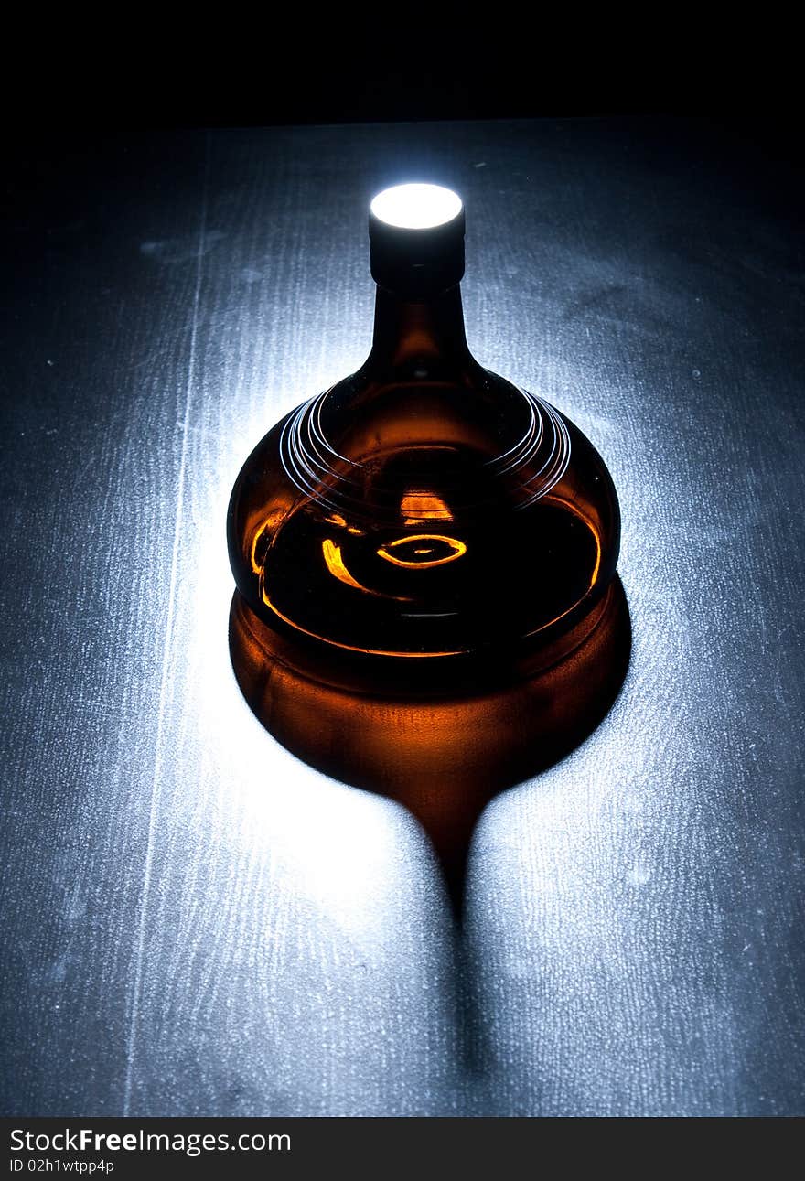 Amber bottle in green spotlight on the floor