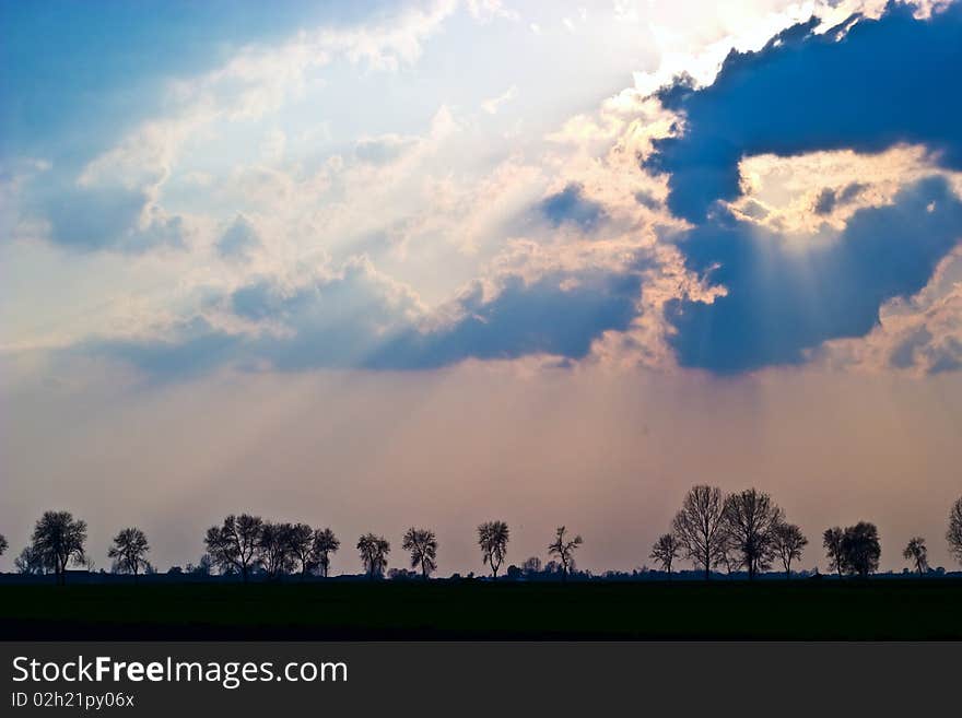 Occurring sun behind the blue clouds on a warm evening