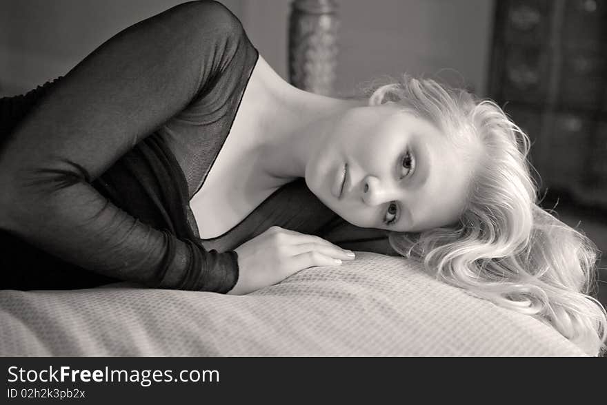 A monochrome portrait of a young woman lying on a bed. A monochrome portrait of a young woman lying on a bed