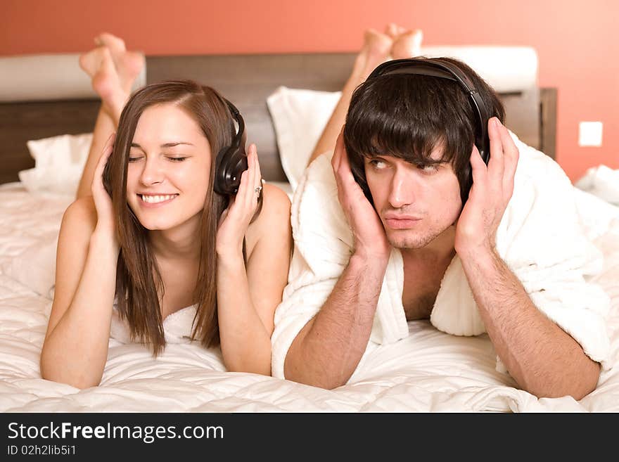 Girl with smile and boy in headphones on bed. Girl with smile and boy in headphones on bed