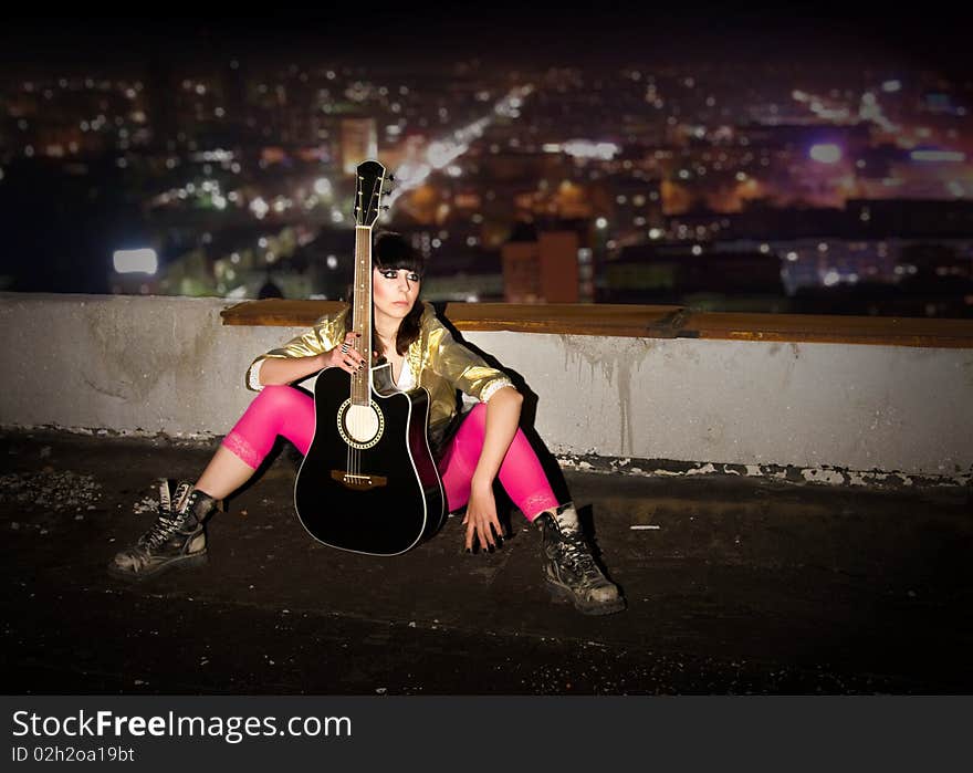 The young girl with a guitar on a roof of a high-rise building. The young girl with a guitar on a roof of a high-rise building