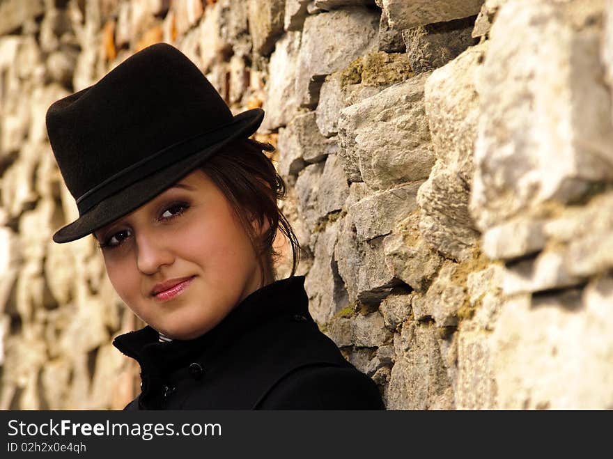 Woman in black felt hat lean-to the stone wall. Woman in black felt hat lean-to the stone wall