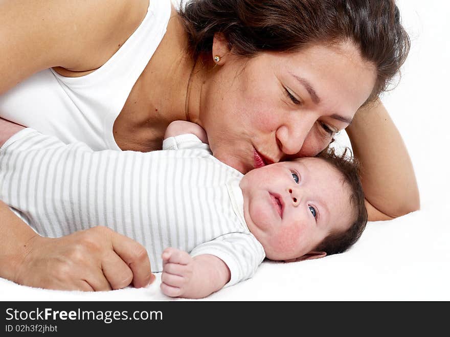 Happy mother and baby lying on the bed and playing