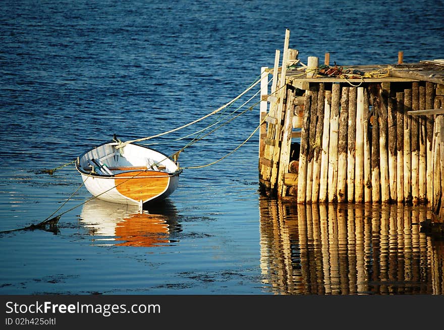 Wooden boat is tied to a crude dock. Wooden boat is tied to a crude dock.