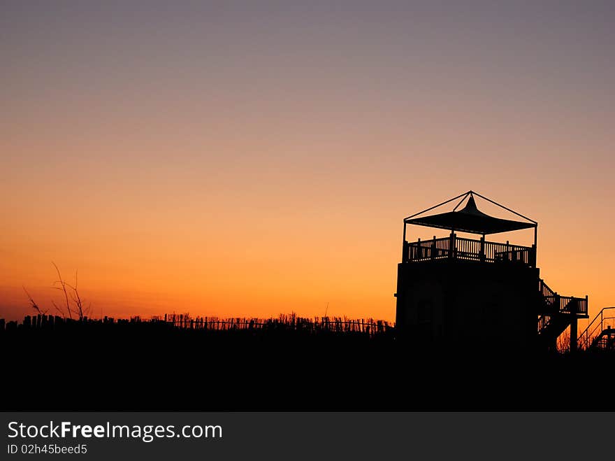 Sunset silhoutte of house with free space above.