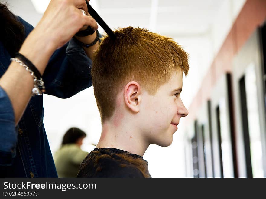 Smiling boy with red hair at the hairdresser